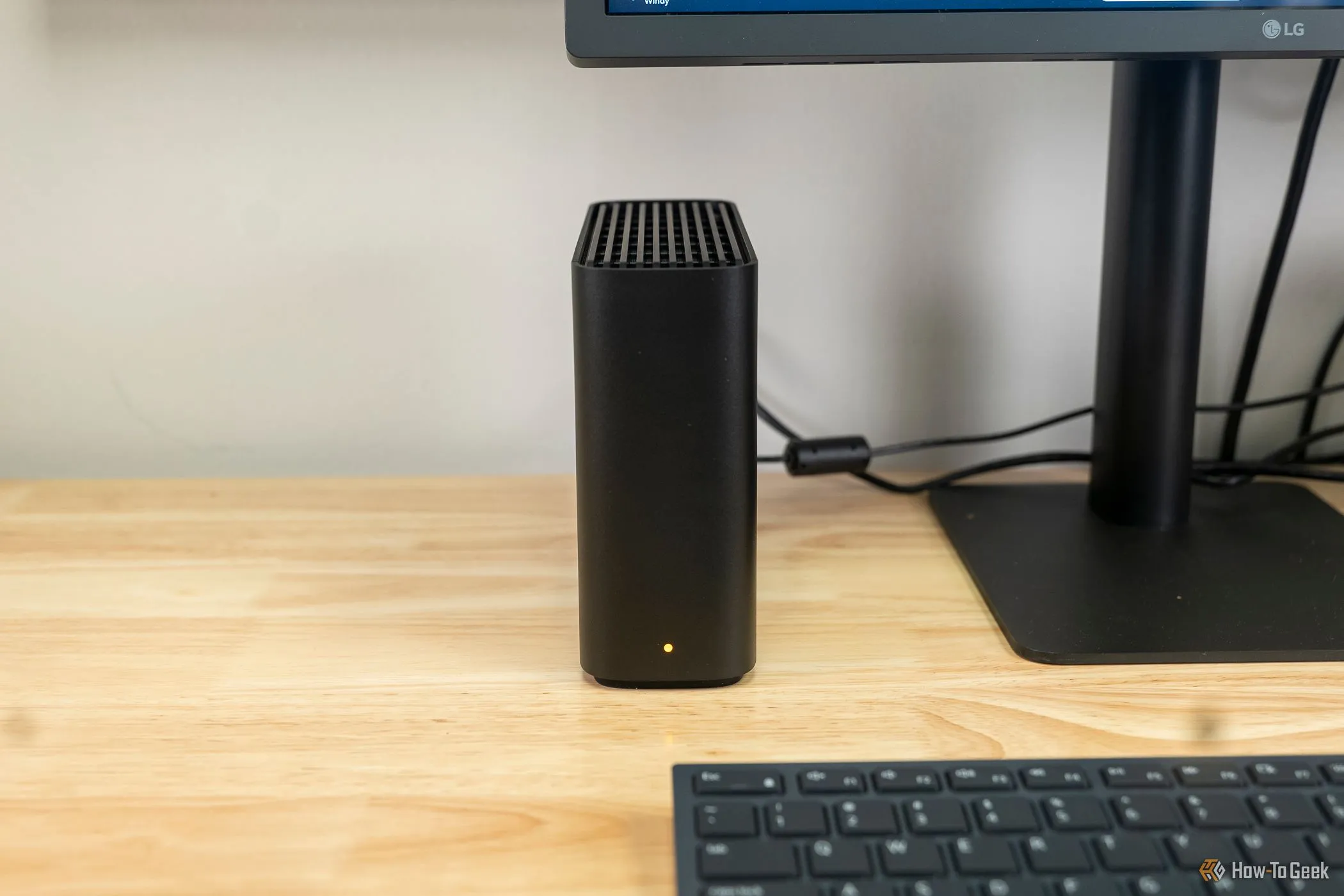 Thiết bị Synology BeeStation (NAS) cạnh màn hình máy tính, cho thấy khả năng chạy Jellyfin qua Docker trên các hệ thống lưu trữ mạng.