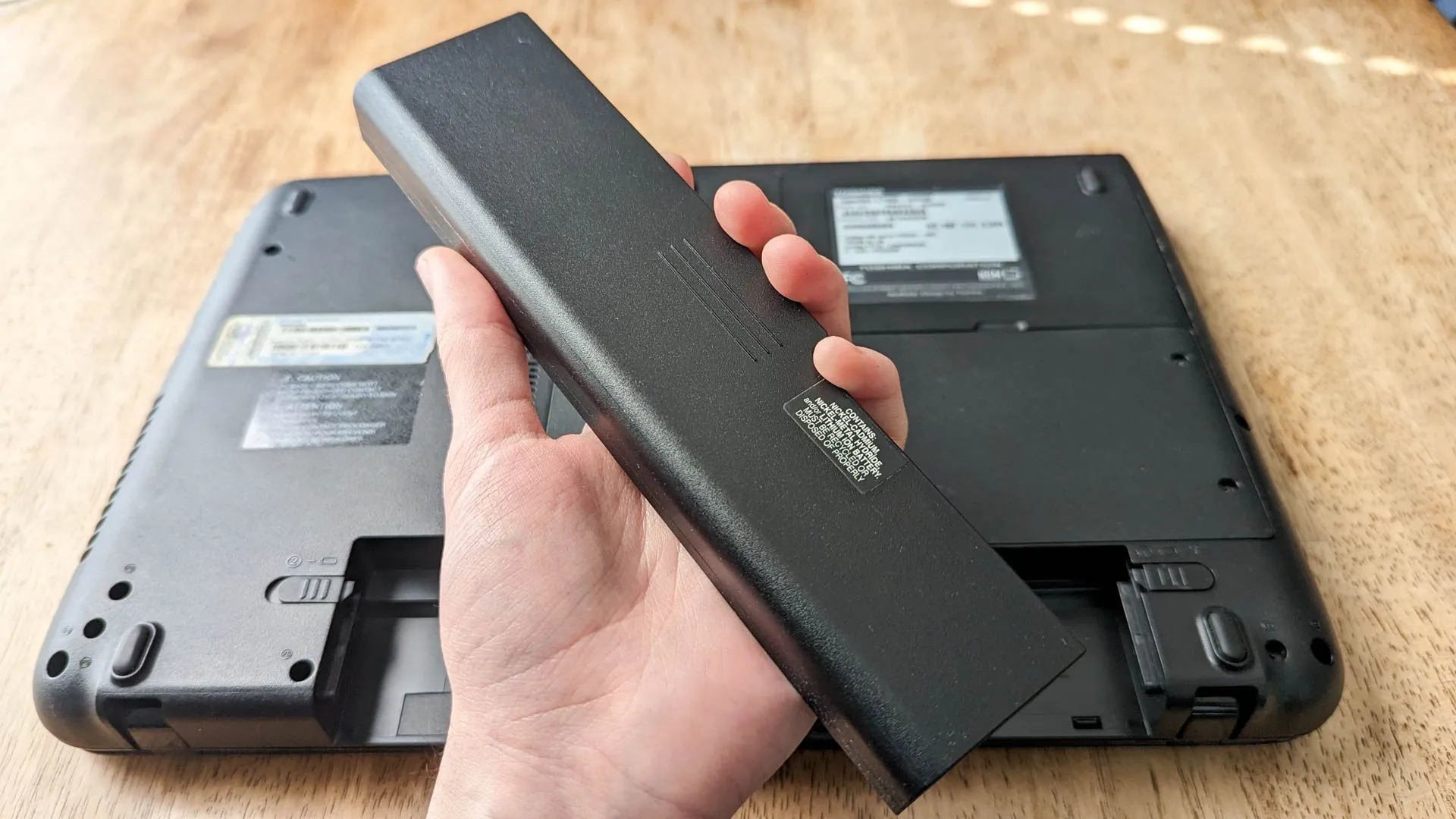 Một người đang cầm trên tay viên pin laptop có thể tháo rời, minh họa cho khả năng thay thế pin